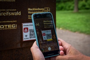 Pressestelle der Universitäts- und Hansestadt Greifswald Mithilfe eines Smartphones wird der QR-Code zum Download der Kloster-Eldena-App gescannt