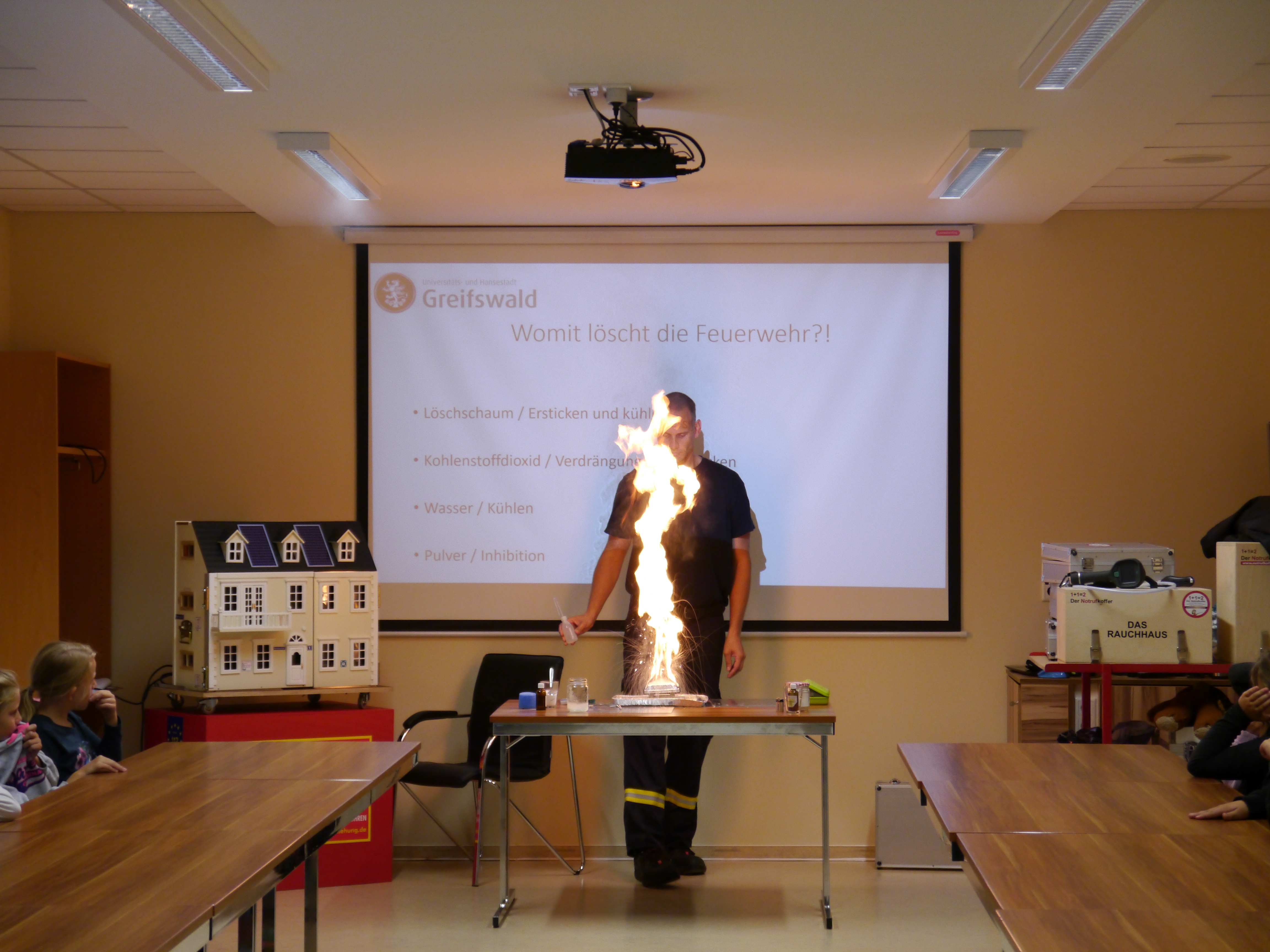 Feuerwehrmann erklärt Kindern ein Experiment mit Feuer