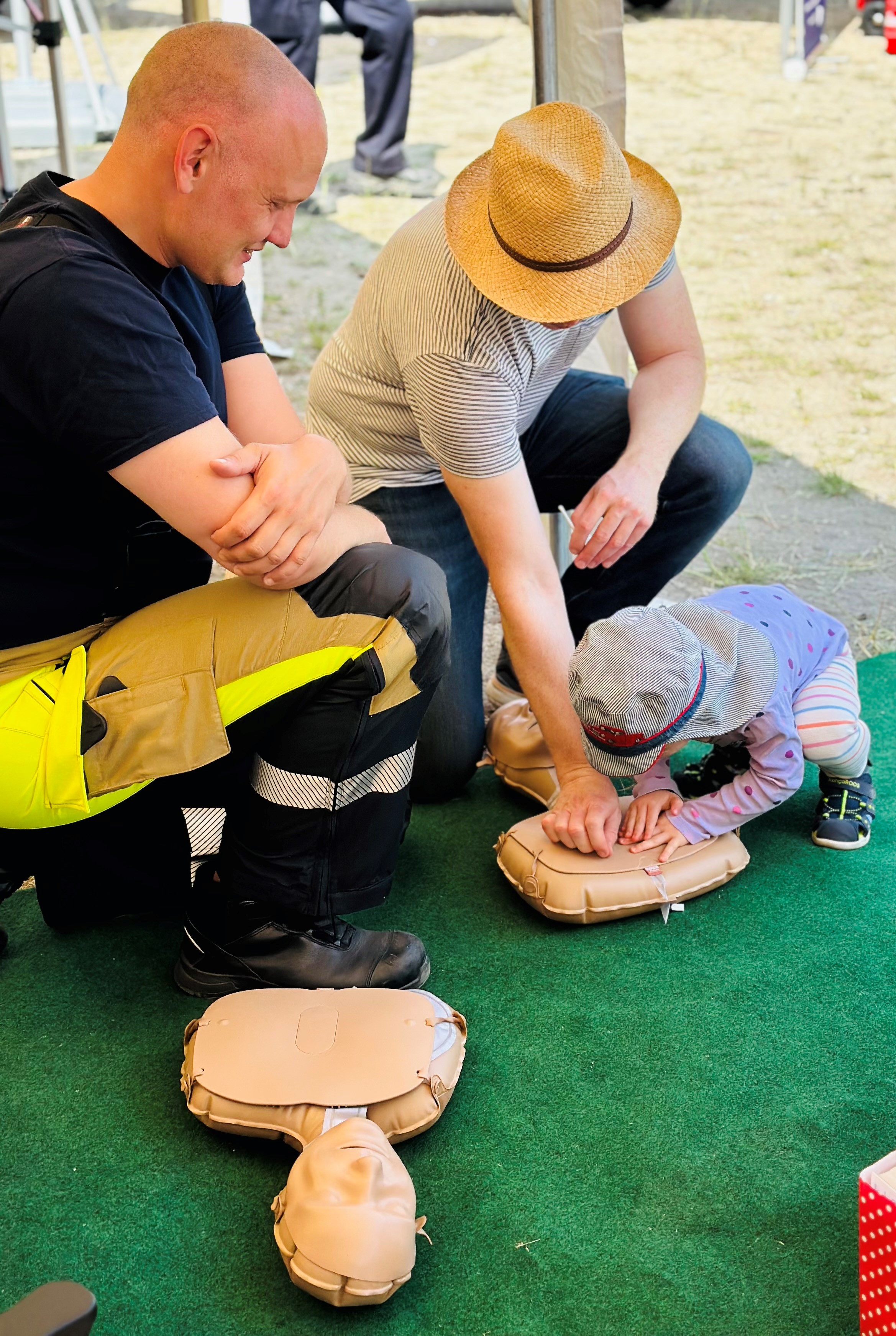 Feuerwehrmann erklärt Kind die Reanimation an einer Puppe