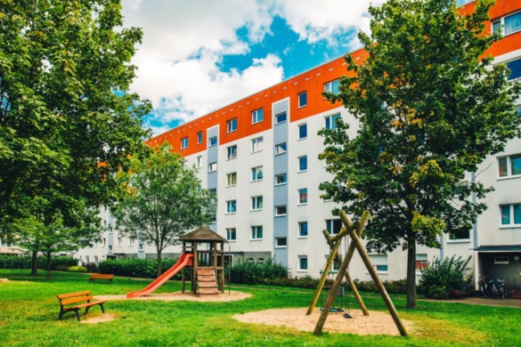 Schönwalde I © Wally Pruß Spielplatz vor einem Gebäude, umgeben von zwei Bäumen