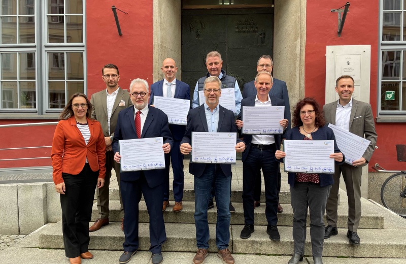 Die Mitglieder des Nachhaltigkeitsbündnisses stehen vor dem Rathaus und halten die unterzeichnete Deklaration hoch.