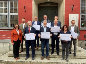 Mitglieder des Nachhaltigkeitsbündnisses unterzeichnen Deklaration 112023 © Pressestelle Die Mitglieder des Nachhaltigkeitsbündnisses stehen vor dem Rathaus und halten die unterzeichnete Deklaration hoch.