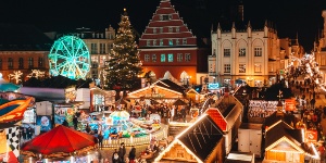 Blick auf den Greifswalder Weihnachtsmarkt von oben in Richtung Rathaus - viele Stände und leuchtenede Lichter im Dunkeln 