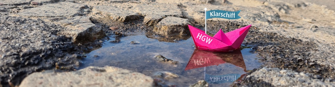 Klarschiff_Banner_1920x500 © Franziska Vopel Auf dem Bild ist eine kaputte Straße. In einem Loch mit Wasser schwimmt ein Papierschiff, auf dessen Fahne steht Klarschiff geschrieben