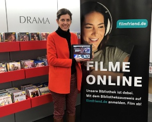 filmfriend_2021 © Stadtbibliothek Leiterin Anja Mirasch vor einem Plakat mit dem neuen Streamingdienst