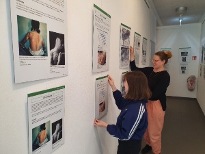 Ausstellung Mayors for peace 2022 © STRAZE Laura Armborst und Juliette Deforge hängen die Plakate für die Ausstellung Bürgermeister für den Frieden in der STRAZE auf