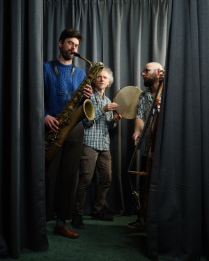 AVA Trio © Erik Smiths Das AVA Trio steht vor einem grauen Vorhand und jeder Musiker hat sein Instrument in der Hand