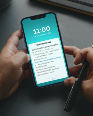 Probewarnung zum bundesweiten Warntag © Bundesamt für Bevölkerungsschutz und Katastrophenhilfe Auf dem Display des Smartphones erscheint eine Nachricht zum Probealarm am 14. September um 11 Uhr