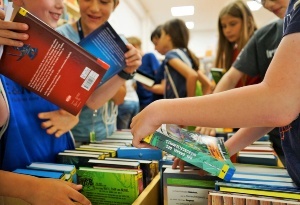 FerienLeseLust © Stadtbibliothek Hans Fallada Mehrere Mädchen und Jungen schauen sich Bücher in einer hölzernen Bücherkiste an