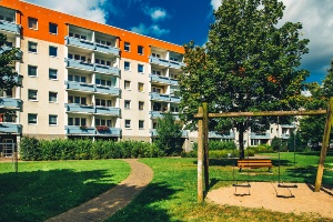 Wohnen in Schönwalde II © Wally Pruß Eine Schaukel und ein Baum stehen vor einem Wohnblock mit Balkonen in Schönwalde II