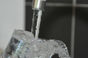 Glas Wasser unter einem laufenden Wasserhahn