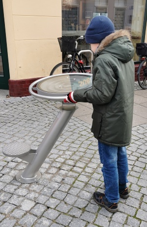 Spielgeräte Schuhhagen_GMG © Greifswald Marketing GmbH ein Junge steht im Schuhhagen vor einem etwa ein Meter großen Edelstahlfuß mit beweglichem Tellerlabyrinth